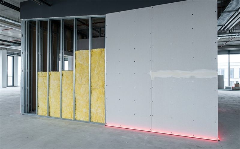 Symbolbild: Trockenbauwand im Bau &ndash; St&auml;nderwerk mit D&auml;mmung, daneben fertig beplankt und verspachtelt